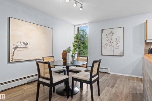 Recessed lighting fixtures illuminate the space, featuring wood-finish flooring and a window offering exterior greenery - #7 10032 113 St Nw, Edmonton, AB 