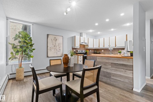 Kitchen featuring white cabinetry, wood-finish countertops, stainless steel appliances, and a wood-finish backsplash - #7 10032 113 St Nw, Edmonton, AB 