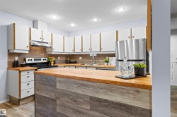 Kitchen featuring white cabinetry, wood-finish countertops, wood-finish backsplash, stainless steel appliances, and recessed lighting - 