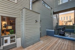 Wood-finish deck with exterior wall sconce, horizontal siding, and multi-level hardscaping with railings - 
