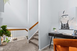 Carpeted hallway with a wood handrail and painted balusters - 