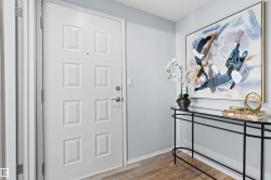 Entryway featuring a paneled door with hardware, neutral wall paint, and wood-finish flooring - 