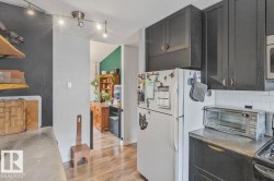 Kitchen featuring dark cabinetry, a white tile backsplash, track lighting, and concrete-finish countertops - 