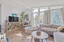 Sloped ceiling with exposed beams, wood-finish flooring, multiple large windows, and a built-in shelving unit - 8808 43 Avenue Nw, Edmonton, AB 