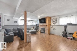 Spacious room featuring wood-finish flooring, a built-in fireplace with a wood-paneled surround, a wood mantel, and multiple windows - 