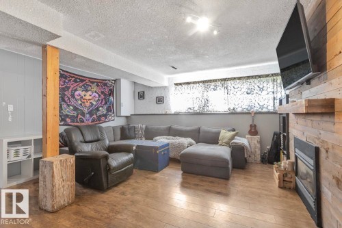 Wood-finish flooring, accent wood wall, built-in fireplace, and integrated shelving - 8808 43 Avenue Nw, Edmonton, AB 