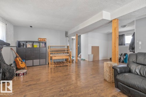 Expansive open-concept room featuring wood-finish flooring, light gray walls, and exposed wood support beams - 8808 43 Avenue Nw, Edmonton, AB 