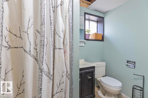 Bathroom with a dark wood-finish vanity, a white toilet, and a window - 8808 43 Avenue Nw, Edmonton, AB 