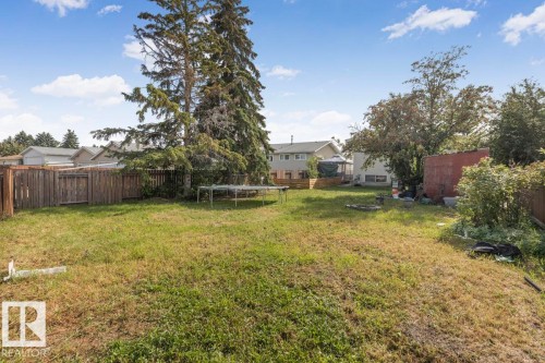 Expansive backyard featuring mature trees, wood fencing, and a storage shed - 8808 43 Avenue Nw, Edmonton, AB 