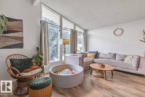 Vaulted ceiling with exposed beam, large picture windows, wood-finish flooring, and white wall finishes - 8808 43 Avenue Nw, Edmonton, AB 