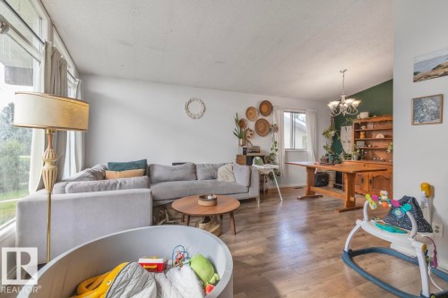 Wood-finish flooring throughout, bright window, and a built-in chandelier - 8808 43 Avenue Nw, Edmonton, AB 