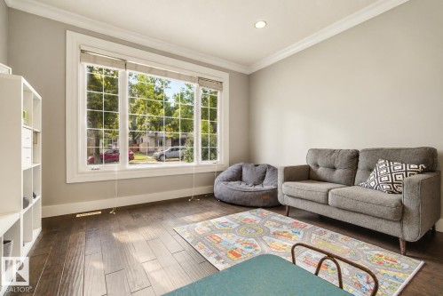 Large window with grid patterns, wood-finish flooring, recessed ceiling lighting, and crown molding - 11 Brunswick Crescent, St. Albert, AB 