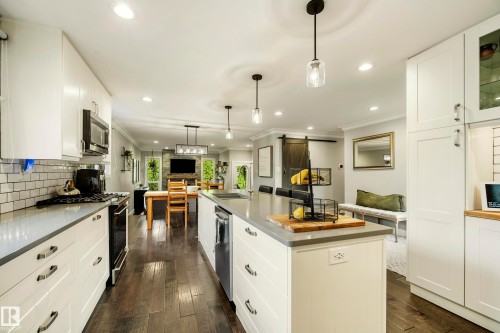 Kitchen featuring white shaker cabinetry, stainless steel appliances, a large center island with seating, and wood-finish flooring - 11 Brunswick Crescent, St. Albert, AB 