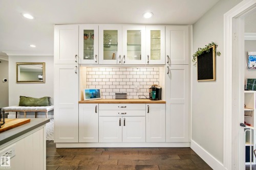 Built-in white cabinetry with glass-front uppers, wood-finish countertop, and subway tile backsplash - 11 Brunswick Crescent, St. Albert, AB 