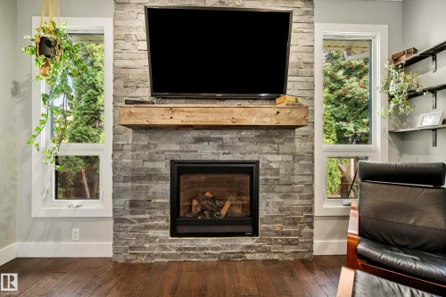 Stone veneer fireplace with a substantial wood mantel, flanked by two vertical windows - 11 Brunswick Crescent, St. Albert, AB 