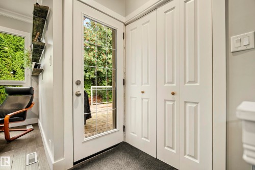 Glass-paneled door with polished hardware, white bi-fold closet doors, and wood-finish flooring - 11 Brunswick Crescent, St. Albert, AB 