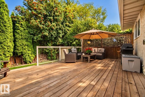 Wood deck with a glass panel railing, lattice privacy screen, and mature perimeter trees - 11 Brunswick Crescent, St. Albert, AB 