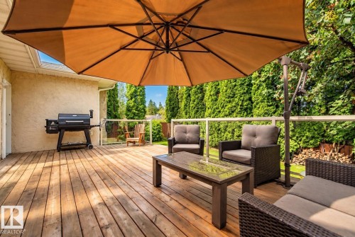 Spacious wood-finish deck with glass panel railing, stucco exterior, and mature perimeter landscaping - 11 Brunswick Crescent, St. Albert, AB 