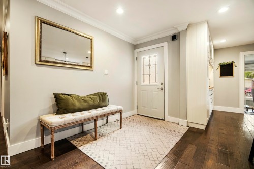 Recessed lighting illuminates the entry, featuring a white paneled door with decorative glass, crown molding, and wood-finish flooring - 11 Brunswick Crescent, St. Albert, AB 