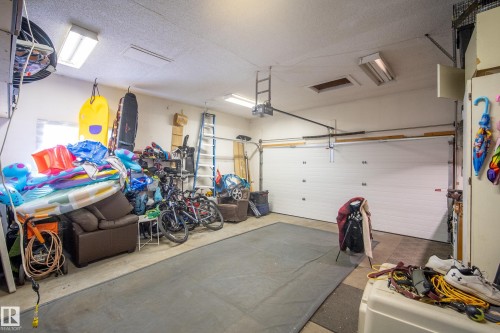 Attached garage with a white panel door, concrete flooring, and overhead fluorescent lighting - 11 Brunswick Crescent, St. Albert, AB 
