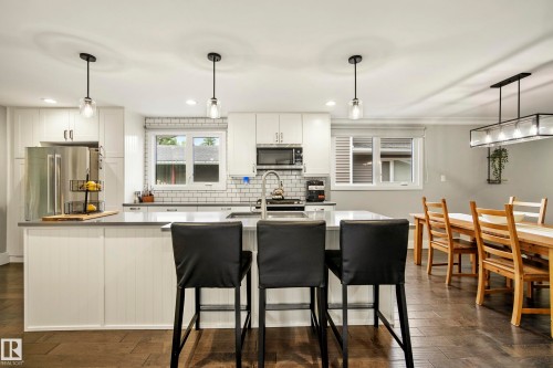 Kitchen featuring white cabinetry, subway tile backsplash, stainless steel appliances, a center island with seating, and wood-finish flooring - 11 Brunswick Crescent, St. Albert, AB 