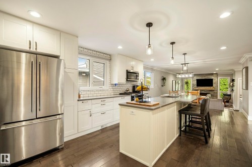 Kitchen featuring stainless steel appliances, white cabinetry, subway tile backsplash, a center island with seating, and wood-finish flooring - 11 Brunswick Crescent, St. Albert, AB 