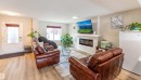 Spacious living area featuring wood-finish flooring, a contemporary electric fireplace with a floating mantel, and a front entry door with decorative glass - 8527 Ellis Link Nw, Edmonton, AB  - Indoor Photo Showing Living Room With Fireplace 