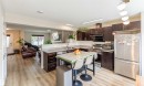 Kitchen featuring dark wood cabinetry, stainless steel appliances, a double basin sink, and wood-finish flooring - 8527 Ellis Link Nw, Edmonton, AB  - Indoor Photo Showing Kitchen With Double Sink 