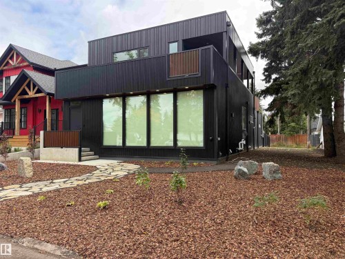 Modern exterior with black vertical siding, multiple large windows, and a second-story balcony with wood-finish railing - 8815 142 Street Nw, Edmonton, AB 
