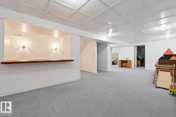 Expansive carpeted area with a built-in wood bar, wall sconces, and a paneled ceiling - 