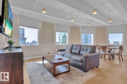 Expansive windows with roller shades, decorative wall paneling, light wood-finish flooring, and recessed ceiling lighting - 