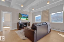 Wood-finish flooring, multiple windows with blinds, recessed decorative wall panels, and exposed beam ceilings with pendant lighting - 