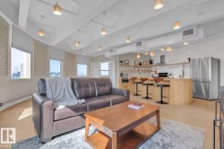 Open-concept living space featuring wood-finish flooring, exposed ductwork, and built-in kitchen appliances - 