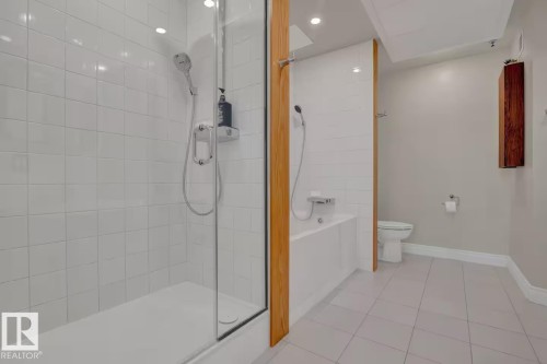 Glass-enclosed shower with white tiled walls, separate soaking tub, and tile flooring - #904 10105 109 St Nw, Edmonton, AB 