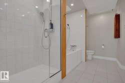 Glass-enclosed shower with white tiled walls, separate soaking tub, and tile flooring - 
