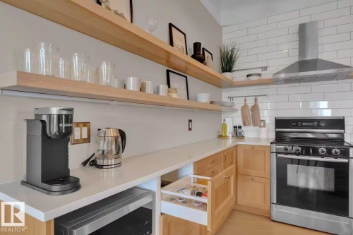 Corner kitchen with white subway tile backsplash, stainless steel range and hood, light wood cabinetry, and open shelving - #904 10105 109 St Nw, Edmonton, AB 