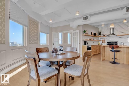 Open-concept living space with wood-finish flooring, multiple windows, and decorative wall paneling - #904 10105 109 St Nw, Edmonton, AB 