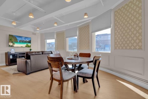 Recessed ceiling with visible ductwork, light wood-finish flooring, multiple windows with cellular shades, and decorative wall panels - #904 10105 109 St Nw, Edmonton, AB 