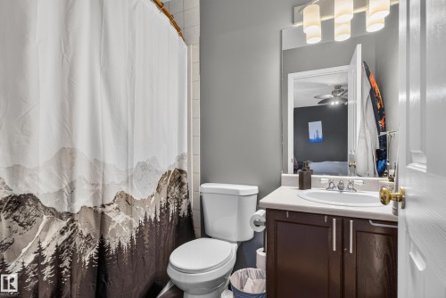 Vanity with a white countertop and dark wood-finish cabinetry, a framed mirror, and a three-light fixture - 9826 180 Avenue Nw, Edmonton, AB 