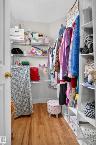 Walk-in closet with wood-finish flooring, white wire shelving, and built-in white shelving - 9826 180 Avenue Nw, Edmonton, AB 