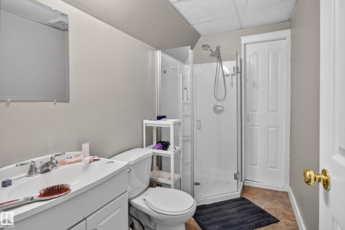 Bathroom featuring a glass-enclosed shower, white vanity with integrated sink, toilet, and a wall-mounted mirror - 9826 180 Avenue Nw, Edmonton, AB 