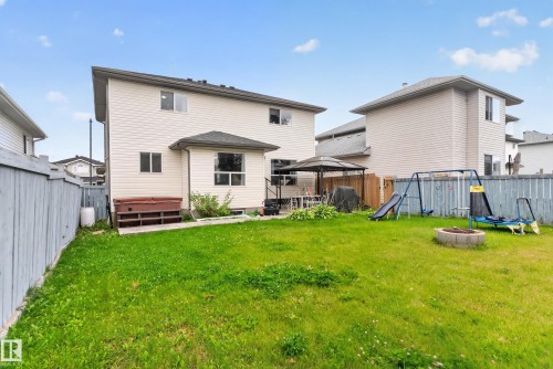 Expansive backyard featuring a manicured lawn, a built-in fire pit, and a privacy fence - 9826 180 Avenue Nw, Edmonton, AB 