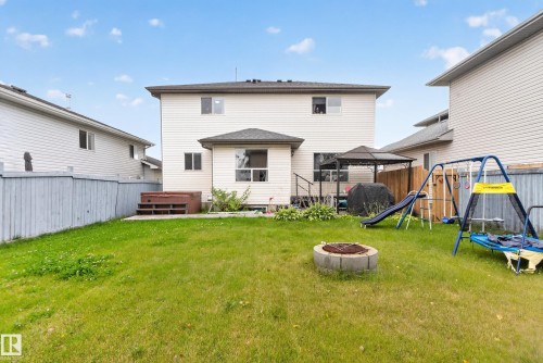 Expansive grassy yard featuring a concrete block fire pit and a raised deck with a gazebo - 9826 180 Avenue Nw, Edmonton, AB 