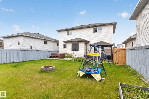 Fenced backyard featuring a fire pit, hot tub, and shaded patio area - 9826 180 Avenue Nw, Edmonton, AB 