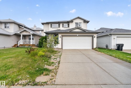 Two-story residence featuring light-colored siding, an attached two-car garage, and a concrete driveway - 9826 180 Avenue Nw, Edmonton, AB 