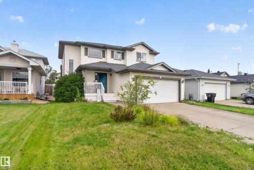 Two-story residence featuring light-colored siding, a covered front entry with white railings, and an attached two-car garage - 9826 180 Avenue Nw, Edmonton, AB 