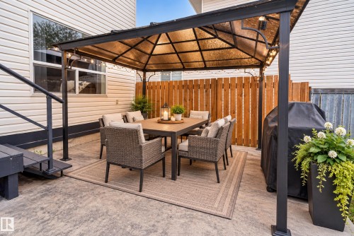 Concrete patio featuring a permanent gazebo with a translucent roof, a wood privacy fence, and vinyl siding - 9826 180 Avenue Nw, Edmonton, AB 