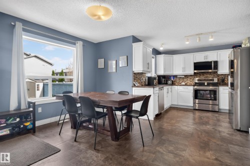 Open-concept kitchen with white cabinetry, stainless steel appliances, and a tiled backsplash - 9826 180 Avenue Nw, Edmonton, AB 