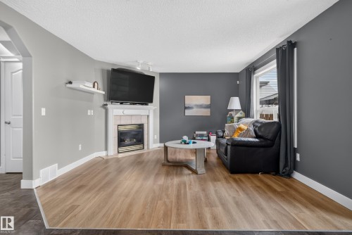 Wood-finish flooring throughout, complemented by a corner fireplace with tile surround and mantel - 9826 180 Avenue Nw, Edmonton, AB 