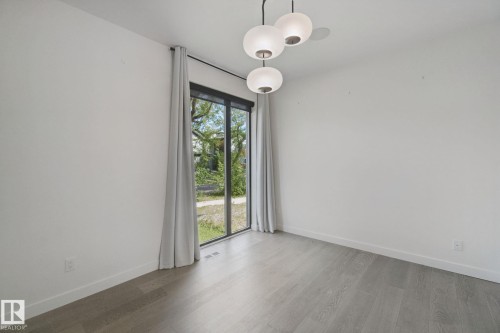 Light wood-finish flooring, white walls, and a contemporary ceiling light fixture - 10925 University Avenue Nw, Edmonton, AB 